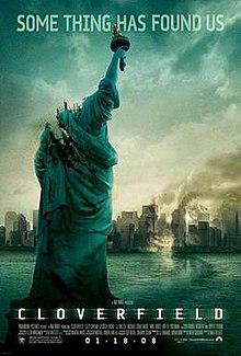 A decapitated Statue of Liberty is in front of a partially wrecked city.