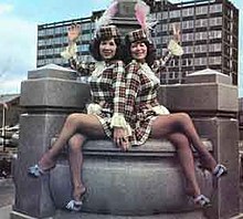 Two women clad in tartan miniskirts and matching hats