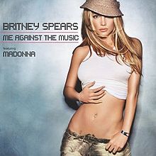 A blonde woman wearing a white top standing in front of a cement wall. The words "Britney Spears Me Against the Music featuring Madonna" are written in capital black letters.