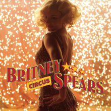 Upper bust of a blond woman. She looks into the camera over her right shoulder. Her mouth is open. She is wearing a black top with small holes. The background is composed by geometric figures in different shades of purple. In an upside down vertical direction, the words "BRITNEY SPEARS" are written in light yellow capital letters. On the lower part of the image, the word "WOMANIZER" is written in capitals with shades of light purple and light yellow.